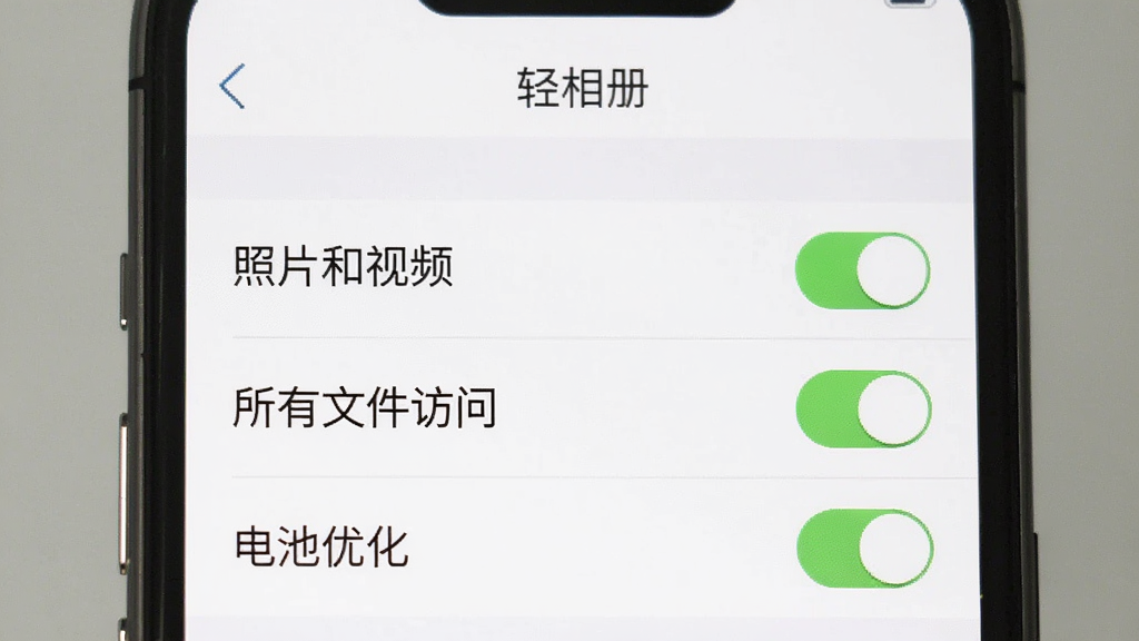 手机屏幕展示“轻相册”的权限设置页面,页面中列出“照片和视频”“所有文件访问”“电池优化”三个权限项,每个权限项右侧有开关按钮,其中“照片和视频”开关为绿色开启状态,背景为白色,风格简洁,画质清晰,无多余元素