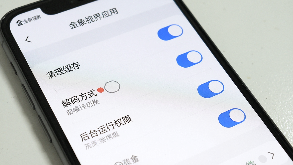 手机屏幕显示金象视界应用设置页面,包含清理缓存、解码方式切换、后台运行权限等选项列表,界面为简洁的白色主题搭配蓝色开关按钮,布局清晰,画面干净无多余装饰,高清画质