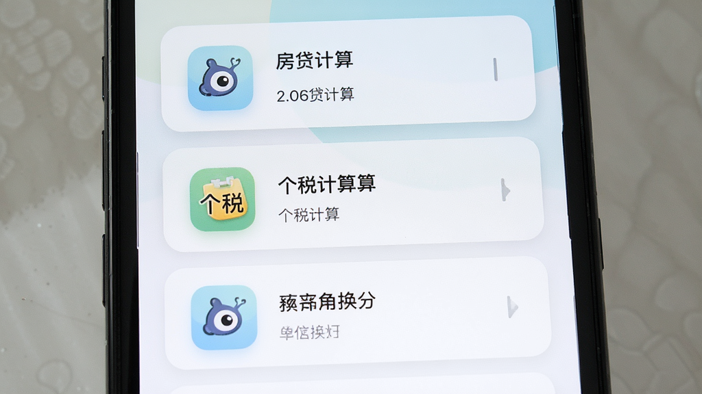 一部手机展示墨鱼通用计算器的生活场景计算列表页面,屏幕中显示房贷计算、个税计算、单位换算等图标入口,主体为手机屏幕特写,布局为纵向列表排列,风格为清新浅色卡片风,细节包含圆角图标与柔和阴影,画质高清,干净,无多余元素