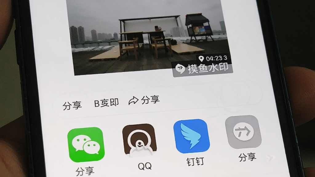 手机屏幕展示摸鱼水印相机的照片分享界面,画面中显示一张带有时间地点水印的已完成照片,下方排列着微信、QQ、钉钉等分享平台图标按钮,界面风格为简洁的社交分享面板,细节包括分享按钮、照片缩略图,画质清晰,干净,无多余元素
