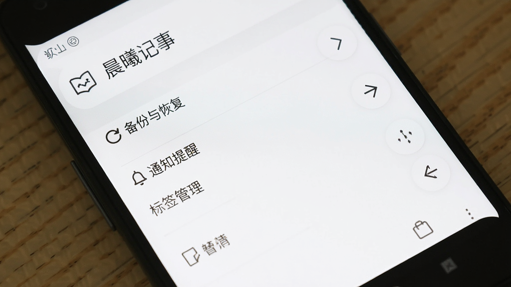 一部安卓手机显示“晨曦记事”的设置页面,页面中有“备份与恢复”“通知提醒”“标签管理”等选项,背景为纯白色,界面风格干净整洁,画质清晰,无多余元素