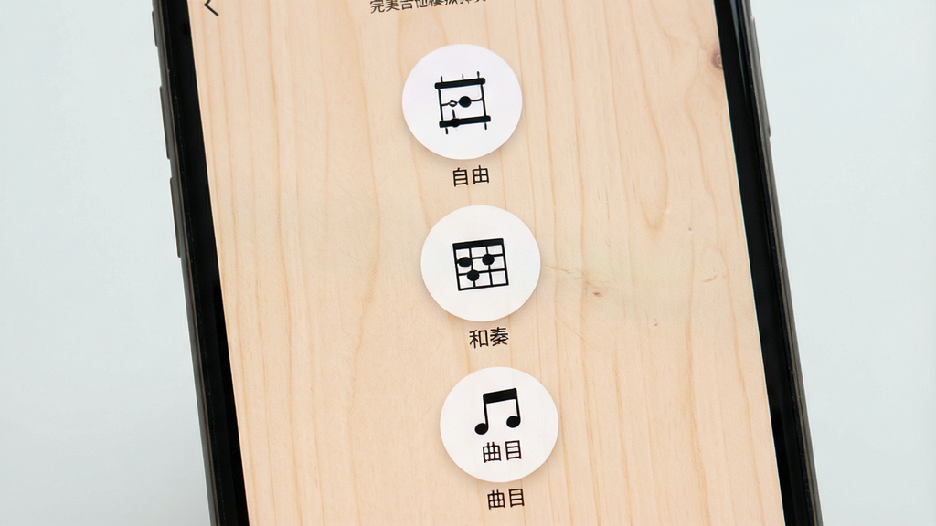 一张展示手机吉他应用内多种模式选择界面的图片,画面为手机屏幕特写,屏幕上分布着三个圆形图标按钮,分别标注着简单的图案代表自由、和弦、曲目,背景为柔和的浅木色,光线均匀,风格清新简洁,布局居中对称,画质细腻,图中包含文字