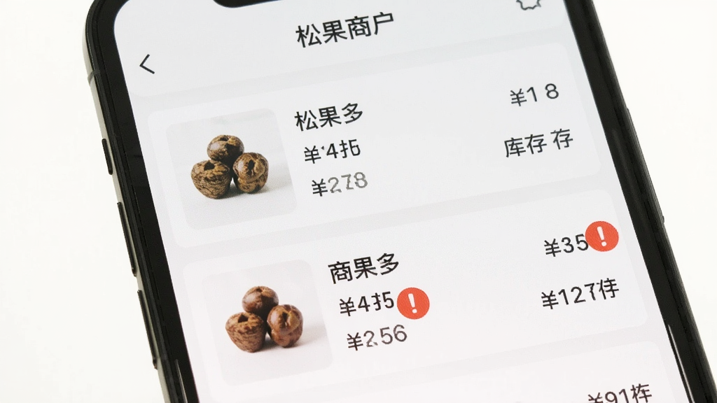 手机屏幕显示“松果商户”商品管理页面,页面中有多个商品条目,每个条目左侧为商品图片,右侧为名称、价格与库存数字,其中两个商品条目的库存数字旁有红色感叹号预警图标,界面布局整齐,配色清淡,画质清晰,无多余元素