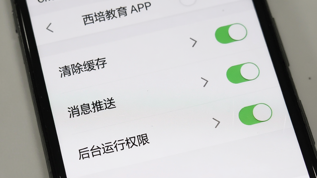 手机屏幕展示西培教育APP设置页面,包含清除缓存、消息推送、后台运行权限等选项,背景是简洁白色界面,布局列表式排列,风格实用工具风,细节包含开关按钮和箭头图标,画质清晰,干净,无多余元素