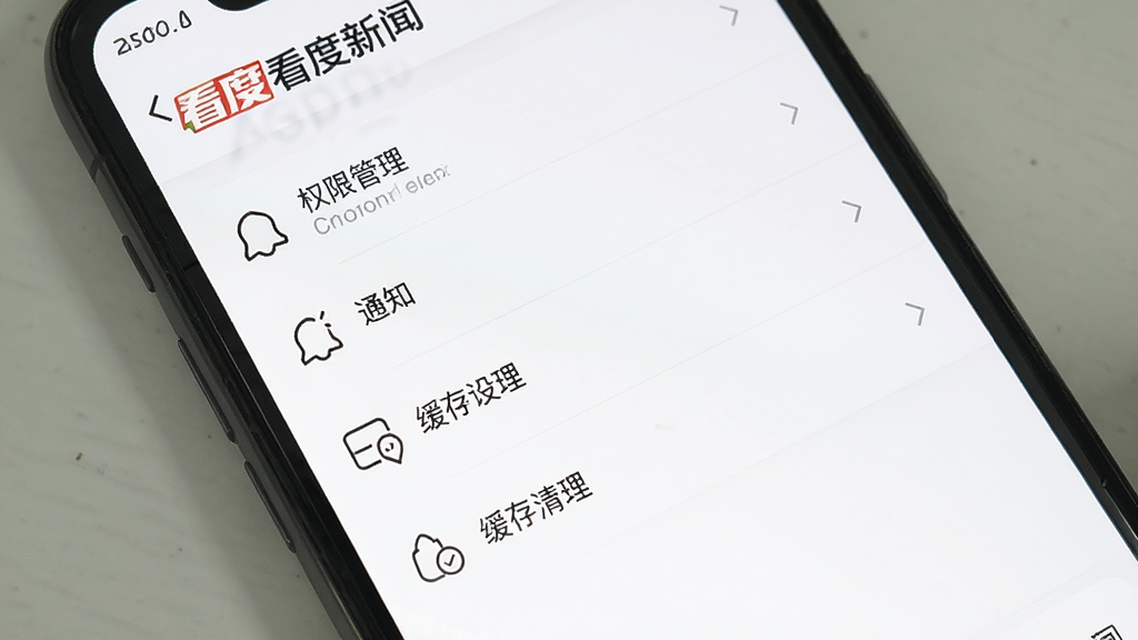 看度新闻APP设置页面,手机屏幕展示权限管理、通知设置、缓存清理等选项,界面采用列表式布局,图标为线性风格,背景为白色,画质清晰,干净无多余元素