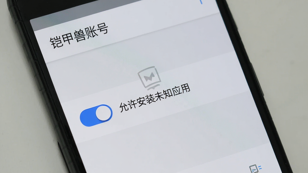 一部安卓手机屏幕中显示铠甲兽账号的安装权限设置界面,界面中有一个开关按钮处于开启状态,旁边写有“允许安装未知应用”字样,界面顶部有“铠甲兽账号”标题,背景为浅灰色系统设置风格,布局为典型安卓设置页面,风格为扁平化系统UI,细节上开关为蓝色,画质清晰干净,无多余元素