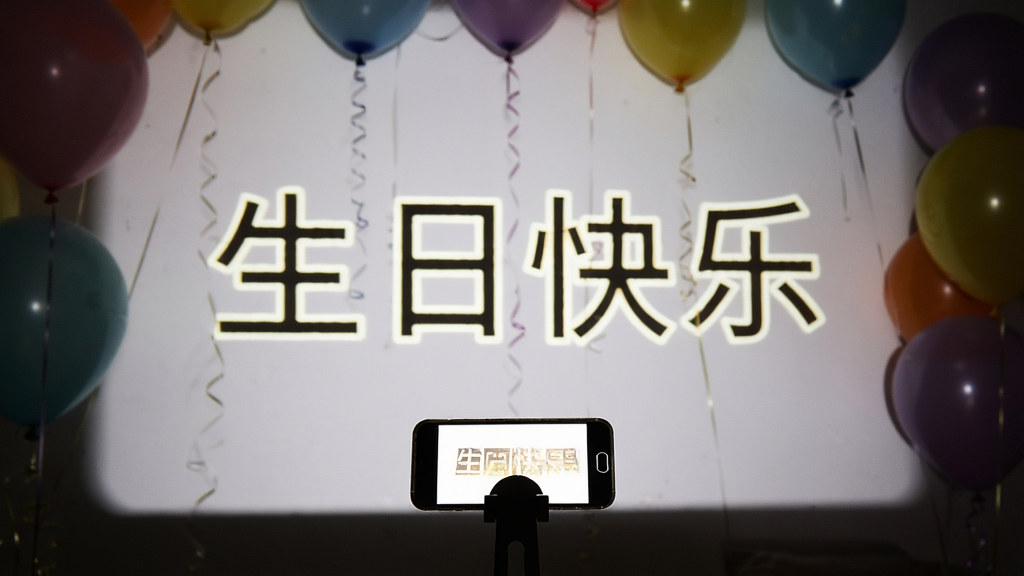 黑暗房间中,一部手机放置在支架上,手机灯光将