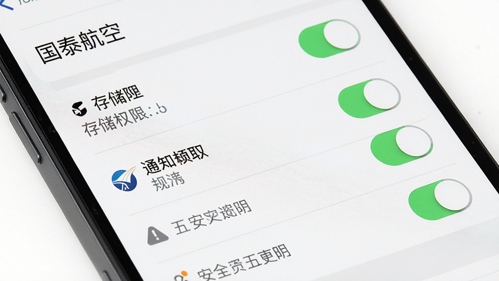 一张展示手机应用安装权限设置界面的示意图,主体为手机屏幕特写显示权限开关列表,布局纵向排列、分区清晰,风格为简洁系统风,细节包含存储权限、通知权限开关与安全提示图标,画质高清干净,图片中可出现文字“国泰航空”