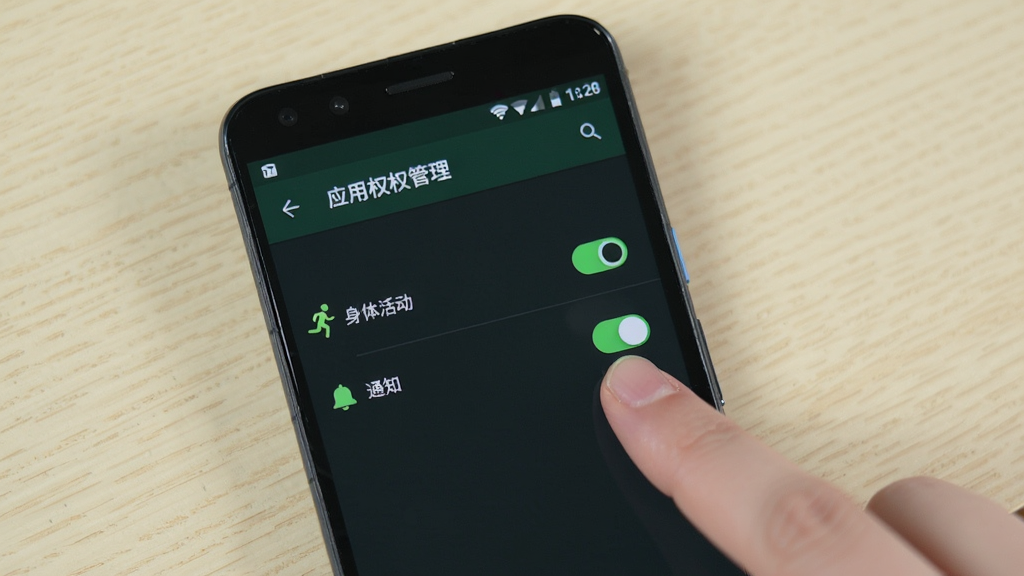运动有福安装设置操作示意图,画面为一部安卓手机屏幕,显示系统设置中的应用权限管理页面,页面中“身体活动”和“通知”两项权限开关处于开启状态,屏幕旁边有一只手正在点击开关,背景为浅色桌面,风格写实清晰,画质干净,无多余文字元素