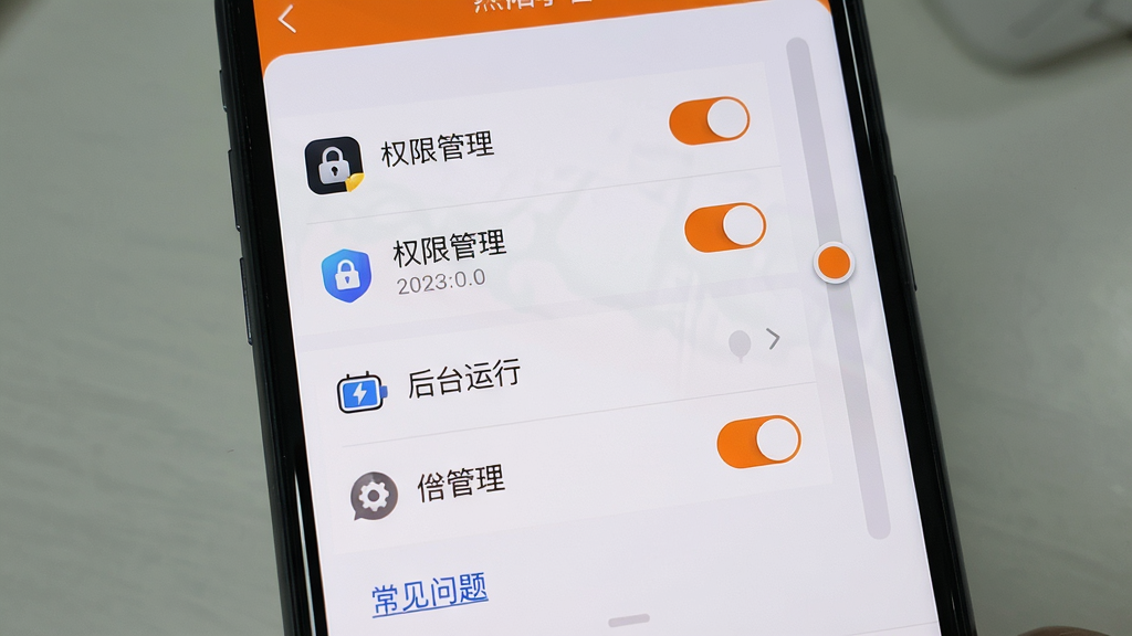 主体:手机屏幕显示烈阳小智的设置界面,有“权限管理”、“后台运行”等选项,页面底部有“常见问题”链接。布局:屏幕居中,设置项列表排列整齐,右侧有滑动条。排版:字体清晰,选项间有分隔线。风格:写实截图风格,色彩真实。细节:设置项包含图标,开关按钮为橙色。画质:高清,干净,无多余元素。