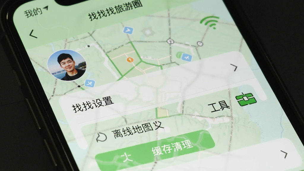 画面主体为一张手机截图,展示“找找找旅游圈”的“我的”页面,包含头像、设置菜单、离线地图入口和工具箱图标。布局为上下排列,风格简洁,背景为浅绿色。细节需清晰显示“找找找旅游圈”字样、WiFi图标、缓存清理按钮。画质干净,突出管理功能与便捷性。