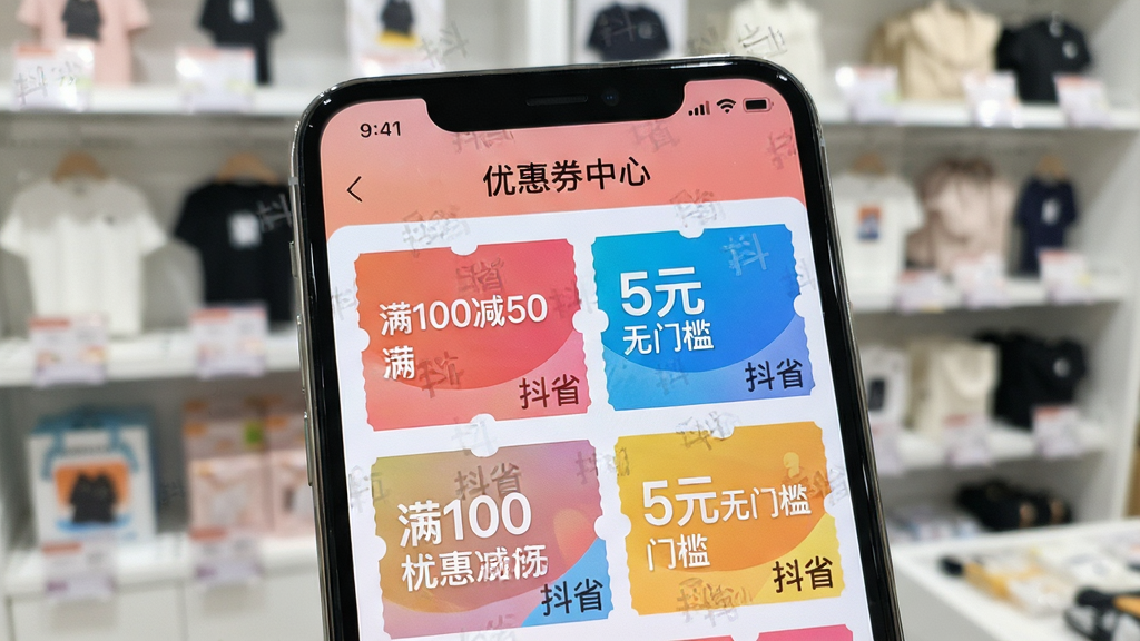 一张抖省APP优惠券中心的界面特写图,展示手机屏幕上排列着各种色彩鲜艳的优惠券卡片,卡片上印有“满100减50”、“5元无门槛”等字样和“抖省”的水印,背景是模糊的商品展示架,布局清晰,风格简约,细节精致,画质干净明亮,无多余元素。