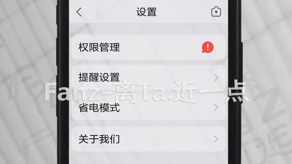 一张手机竖屏截图,显示Fanz-离Ta近一点的设置页面,页面顶部有“设置”标题,下方列表包含“权限管理”、“提醒设置”、“省电模式”、“关于我们”四个选项,其中“权限管理”选项右侧有一个红色感叹号图标,背景为浅灰色,整体界面简洁明了,图片上带有软件名称“Fanz-离Ta近一点”的水印。