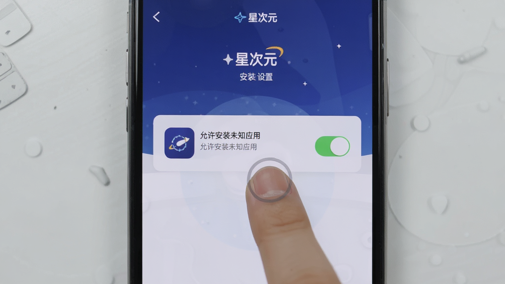 展示“星次元”应用安装与设置界面,手机屏幕显示“允许安装未知应用”开关,背景为浅灰色桌面,风格简洁,布局居中,细节有手指点击图标,画质清晰,干净无多余元素
