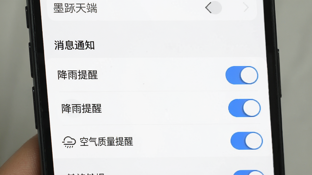 墨迹天气手机端设置界面截图,画面展示“消息通知”设置项,下方有“降雨提醒”、“空气质量提醒”等开关选项,界面风格简洁清晰,背景为白色,开关按钮为蓝色,整体观感干净利落,画质高清,无多余元素