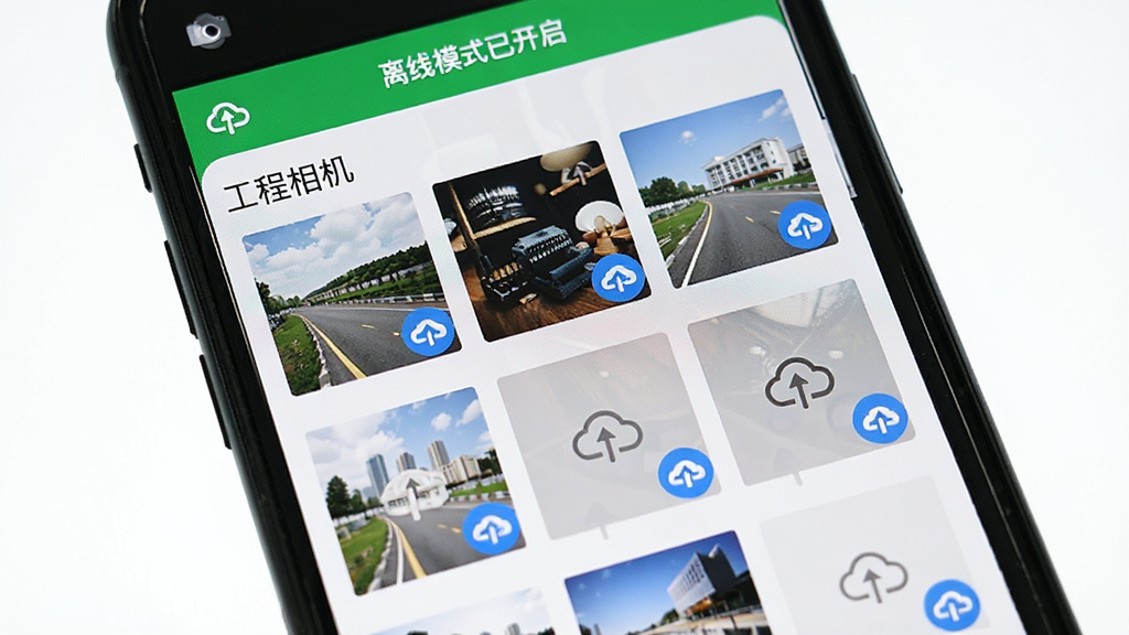 主体为一部手机界面,屏幕显示“工程相机”的离线模式操作界面,界面顶部有“离线模式已开启”的绿色横幅,下方为照片缩略图列表,每张缩略图右下角有云上传图标,其中部分图标显示为灰色待上传状态,另一部分显示为蓝色已上传状态,布局为列表式,风格简洁直观,细节展示离线与上传状态图标的区别,画质干净明亮,无多余元素,图片中文字应包含“工程相机”及“离线模式”字样。