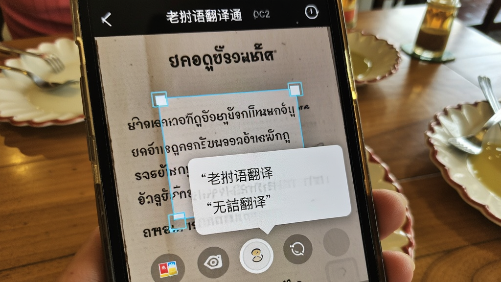 手机摄像头对准一张老挝语菜单,屏幕中显示