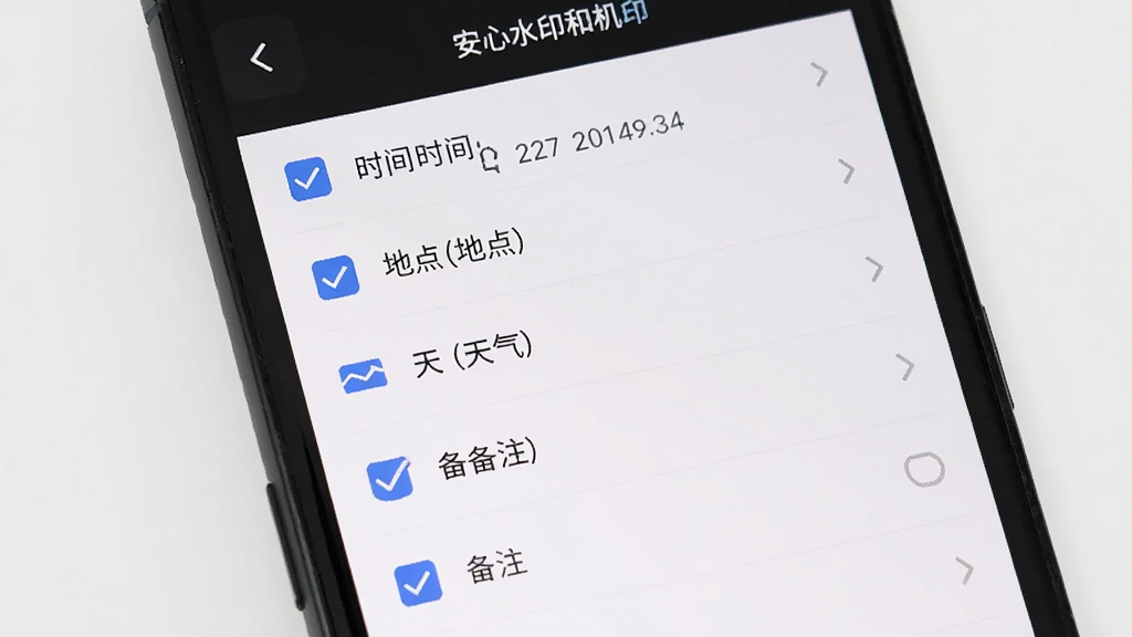 主体为手机屏幕显示安心水印相机水印编辑面板,面板上列有时间、地点、天气、备注等多个勾选项,布局为上下排列的选项列表,排版整齐,风格为扁平化UI设计,细节包括勾选框和文字标签,画质清晰,画面干净,无多余元素