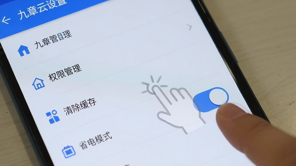 一部安卓手机屏幕显示九章云设置页面,页面中有权限管理、清除缓存、省电模式等选项,旁边有手指点击省电模式开关的示意,风格简洁明了,蓝白配色,画质清晰,无杂乱元素