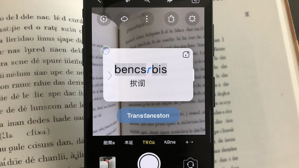 一张展示法语助手拍照取词功能的图片,画面中手机摄像头对准一本法语书,屏幕上叠加显示识别出的单词与中文释义,风格现代,细节包括取词框与翻译按钮,画质清晰,无多余元素
