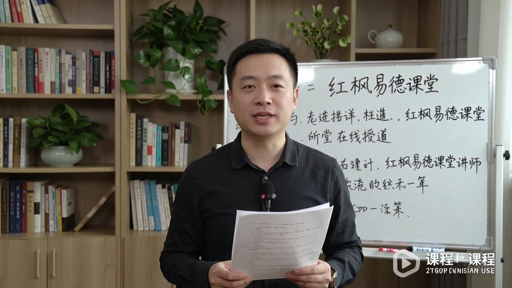 红枫易德课堂讲师在线授课场景,主体为一位讲师在书房中面对镜头讲解,布局为人物居中,背景为书架与绿植,排版自然,风格为文化教育类视频截图,细节包括讲师手持讲义、白板上的板书、画面右下角的课程水印,画质清晰干净,无多余元素