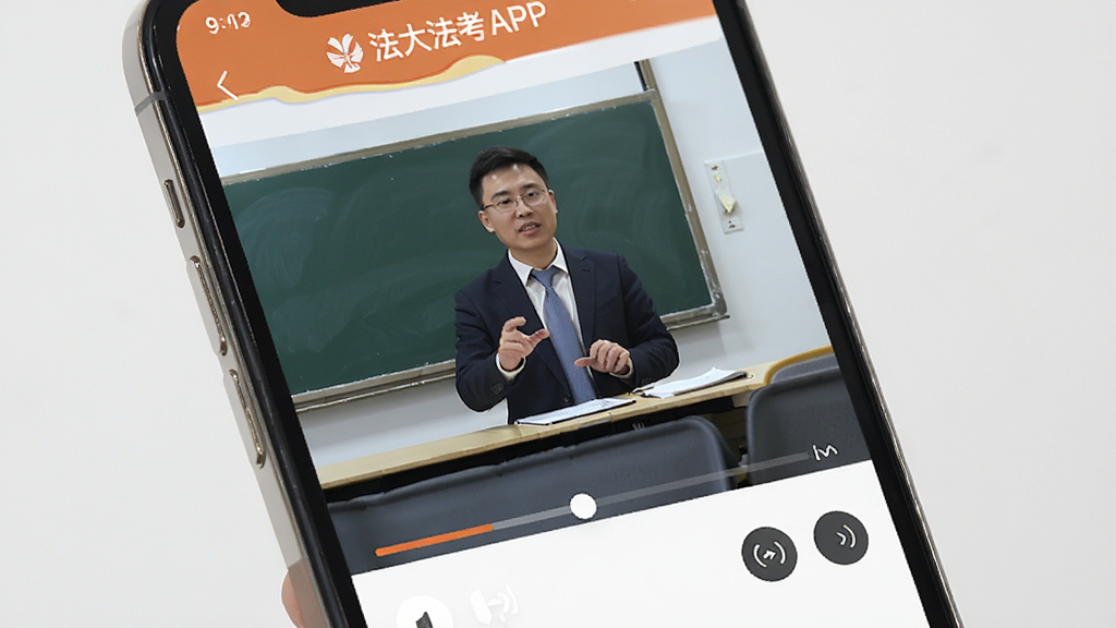 手机屏幕展示法大法考APP的视频课程播放界面,画面中有讲师授课画面,下方有进度条和倍速按钮,界面风格专业简洁,画质清晰干净,无多余元素