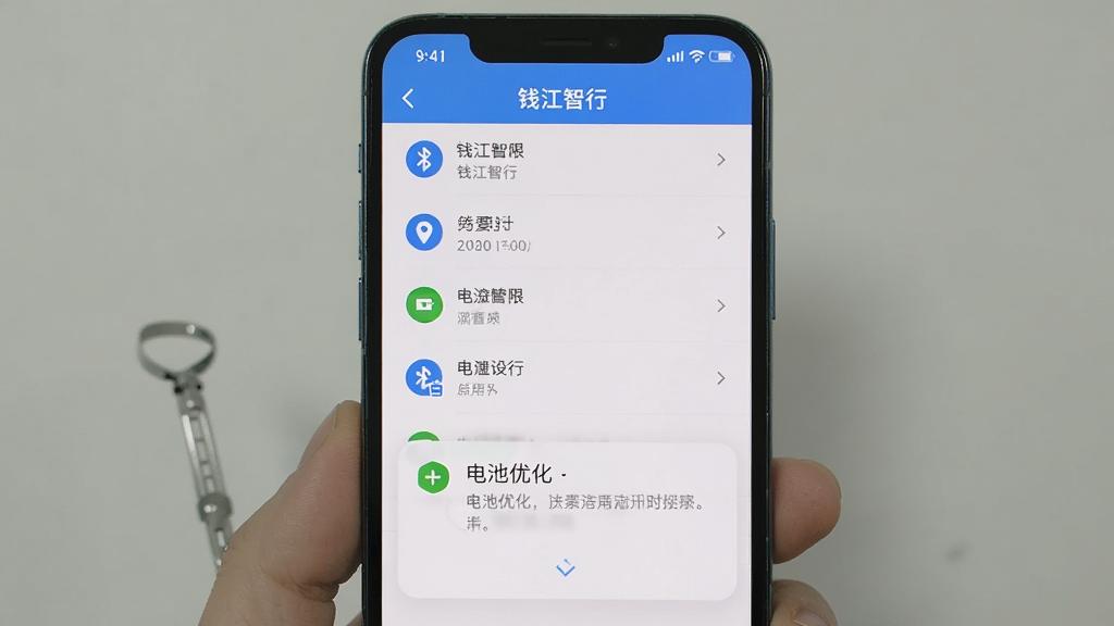 主体是手机屏幕显示“钱江智行”的权限设置页面,布局为上下结构,上方是权限列表,下方是电池优化提示弹窗,排版清晰,风格为实用教程风,细节包括蓝牙图标、定位图标、电池图标,画质清晰,画面干净,无多余元素
