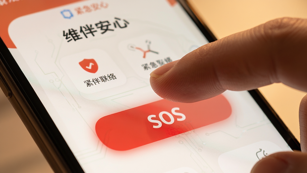 画面主体是一只手指即将触碰手机屏幕上的红色SOS按钮,屏幕背景是维伴安心的紧急联络界面;布局为特写镜头,手指与按钮占据画面中心;排版简洁,视觉焦点明确;风格为写实科技感,色调偏暖;细节上按钮有微弱的红光;画质高清,干净,无多余元素。