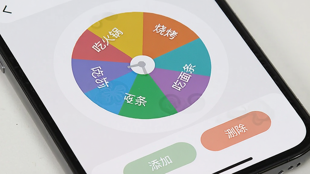 手机界面特写,展示小决定幸运转盘记事本笔记的转盘编辑页面,转盘被分成多个彩色扇形区域,每个区域写有不同选项文字如“吃火锅”“吃烧烤”“吃面条”,下方有添加和删除按钮,背景为浅灰色,风格简洁明快,布局清晰,画质干净,无多余元素