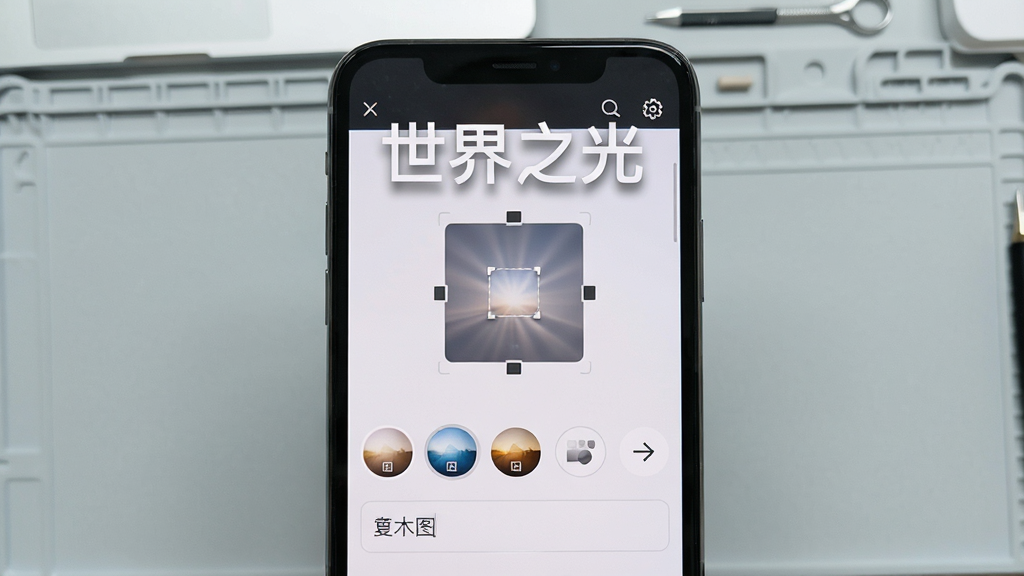 画面中央是一部手机,手机屏幕显示壁纸编辑界面,界面上有裁剪框、滤镜选项和文字输入框,屏幕上方漂浮着“世界之光”字样。布局采用手机正面特写,风格为简洁UI展示风,细节上界面元素清晰,背景为浅灰色工作台。画质清晰,干净,无多余元素。